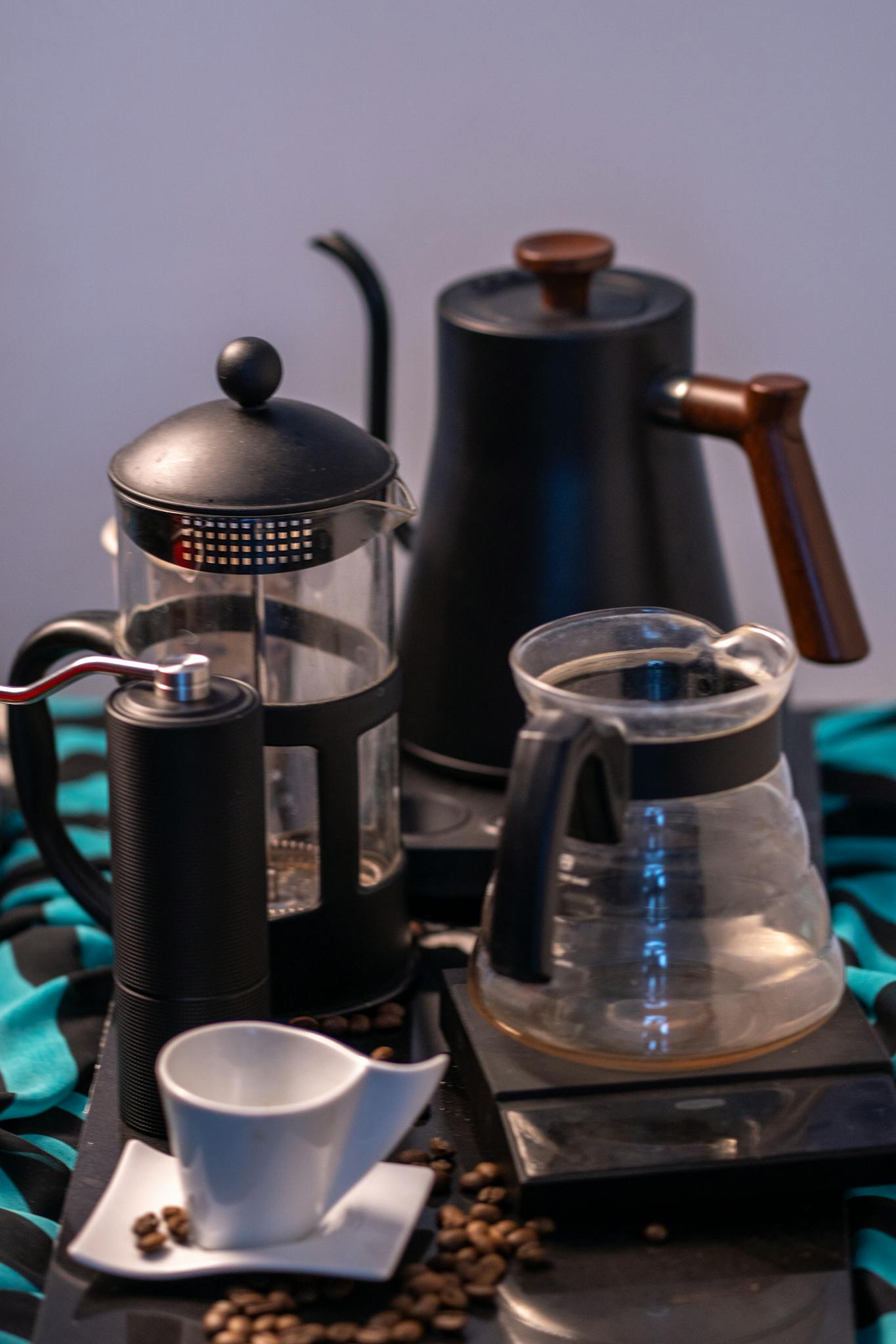 A sophisticated coffee brewing setup featuring a French press and grinder with scattered beans on a table.